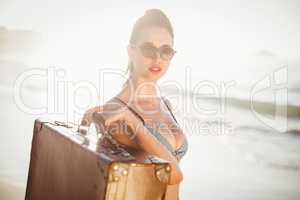 Glamorous woman in bikini holding an old suitcase