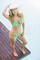 Beautiful woman in green bikini standing by pool side