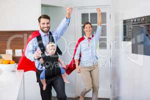 Cheerful family in superhero costume with baby