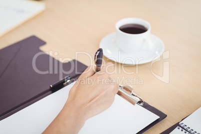 Close-up of female doctors hand writing on clipboard