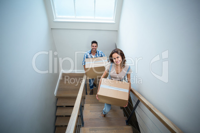 High angle portrait of smiling couple holding cardboard boxes wh