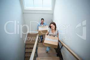 High angle portrait of smiling couple holding cardboard boxes wh