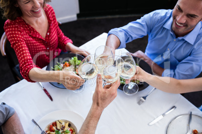 Happy friends toasting wine glass while having lunch