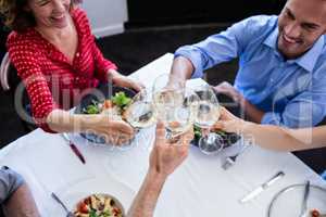 Happy friends toasting wine glass while having lunch