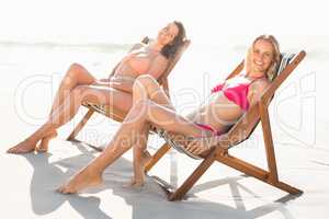 Portrait of two women relaxing on armchair on the beach