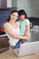 Portrait of smiling mother carrying daughter with laptop