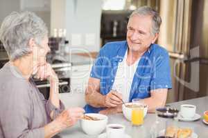 Happy senior couple talking while having breakfast