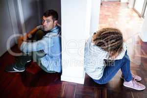 Couple sitting on opposite sides of the wall