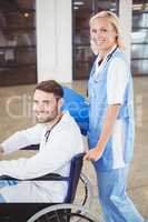 Portrait of smiling doctor on wheelchair with female colleague
