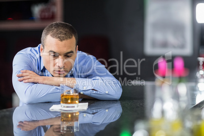 Depressed businessman looking at whisky glasses