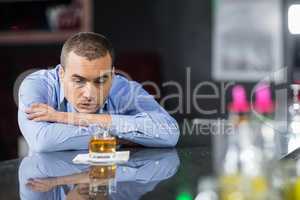 Depressed businessman looking at whisky glasses