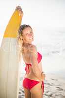 Woman in bikini standing with a surfboard on the beach