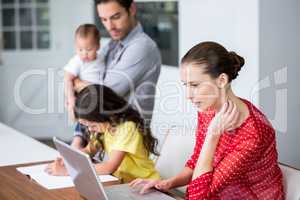 Mother working on laptop with daughter studying