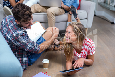 Woman showing digital tablet to male friend at home