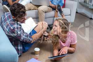 Woman showing digital tablet to male friend at home