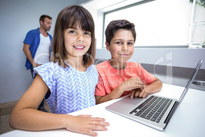 Happy boy and girl using laptop