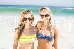 Portrait of two happy women in bikini standing on the beach