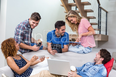 Young friends using modern technologies on sofa