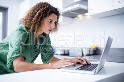 Woman working on laptop in kitchen