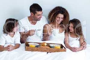 Happy family sitting with breakfast tray on bed
