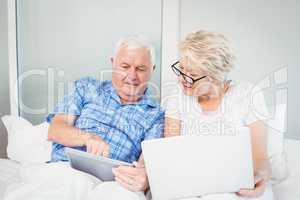 Senior man pointing at tablet with wife