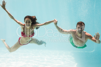 Portrait of smiling couple holding hands while swimming