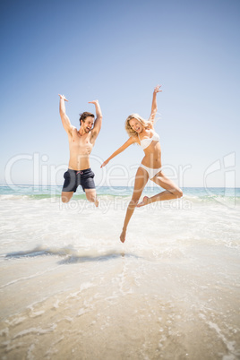 Happy couple jumping on the beach