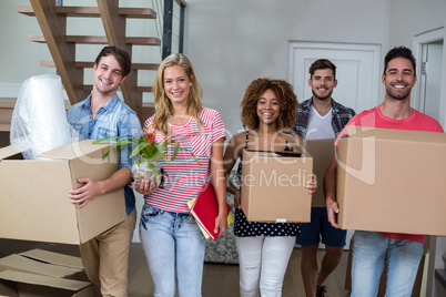 Friends smiling while carrying carton in new house