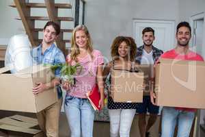 Friends smiling while carrying carton in new house