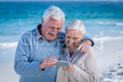 Cute mature couple looking at smartphone