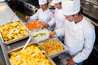 Chefs standing at serving trays of pasta
