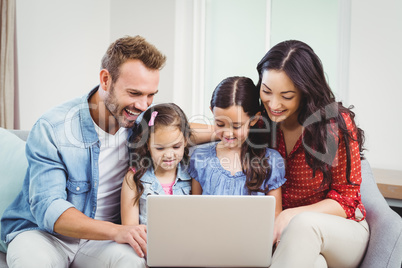 Family smiling and looking in laptop on sofa Family smiling and looking in laptop on sofa