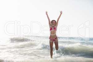 Excited woman in bikini jumping on the beach