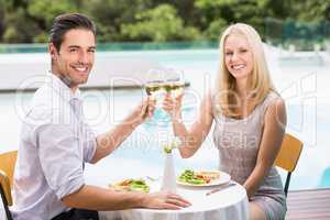 Portrait of happy couple toasting white wine glasses