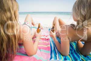 Women lying on the beach with beer bottle