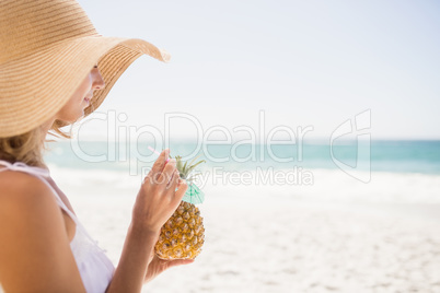 Woman drinking cocktail in pineapple