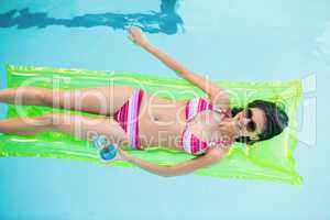 Happy woman in bikini lying on air bed in swimming pool