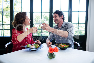 Happy middle-aged couple toasting champagne flutes while having