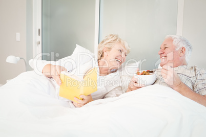 Senior couple reading book in bed