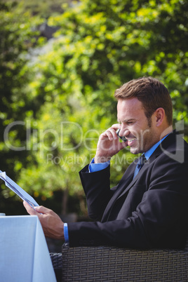 Handsome businessman on the phone and reading the menu