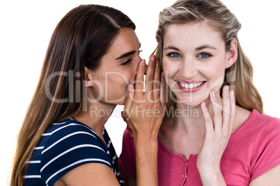 Smiling woman telling secret to friend while standing