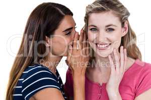 Smiling woman telling secret to friend while standing