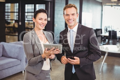 Happy businessman and businesswoman with digital tablet and mobi
