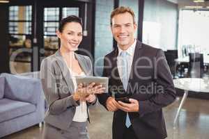 Happy businessman and businesswoman with digital tablet and mobi