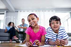 Portrait of brother and sister lying on floor and drawing