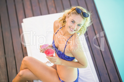 Portrait of beautiful woman with cocktail sitting on sun lounger
