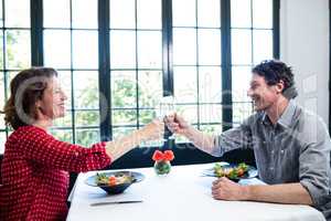 Middle-aged couple toasting champagne flute while having lunch