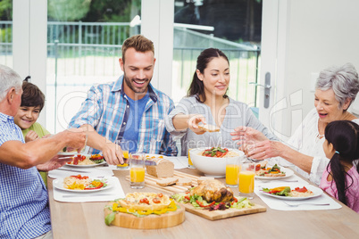 Smiling multi generation family having food at dining table