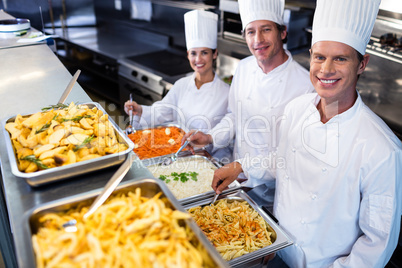 Chefs standing at serving trays of pasta