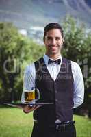 Handsome waiter holding a tray with a pint of beer